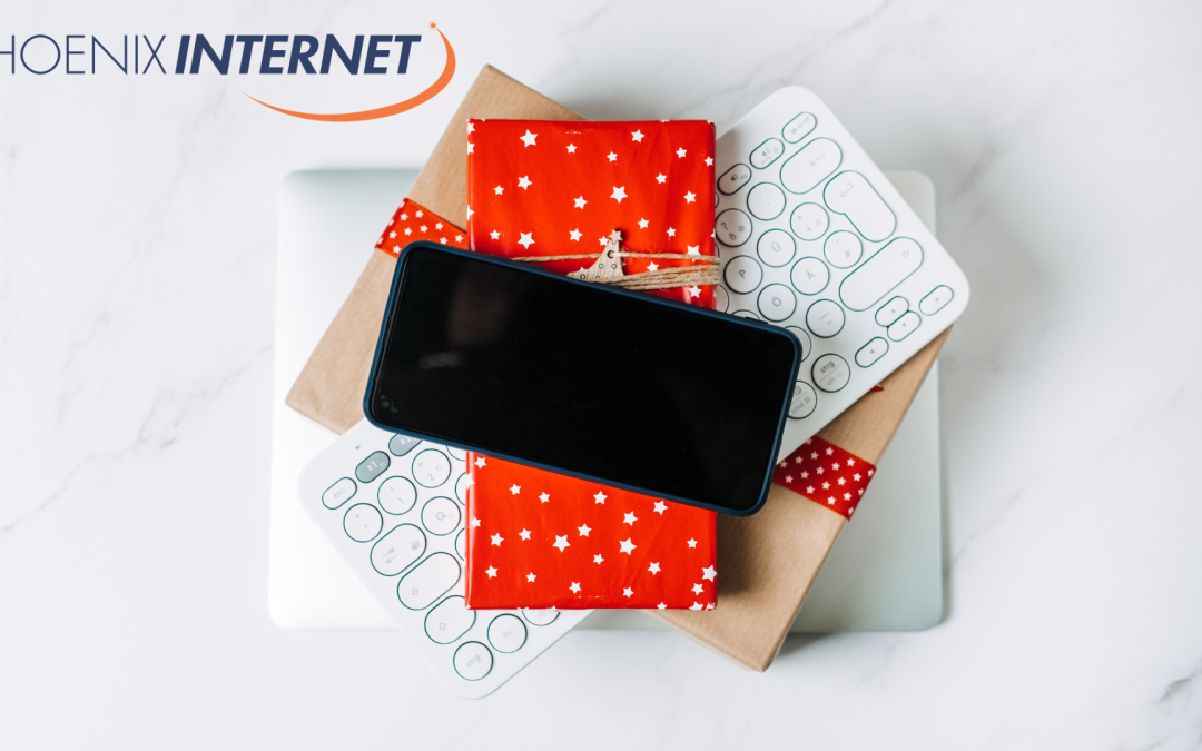 Tech gifts including a wrapped present, smartphone, and compact keyboard, ideal for the holiday season, with the Phoenix Internet logo for seamless internet setup